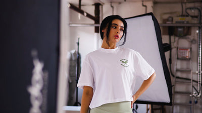 model wearing white oversized t-shirt in eggnog with tennis embroidery to the chest. modelling in manchester, united kingdom