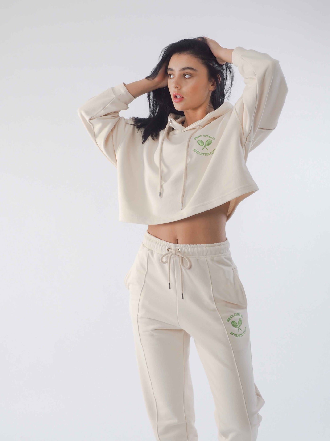 Model is posing in an eggnog tracksuit from WKND Apparel. Hoodie is cropped.
