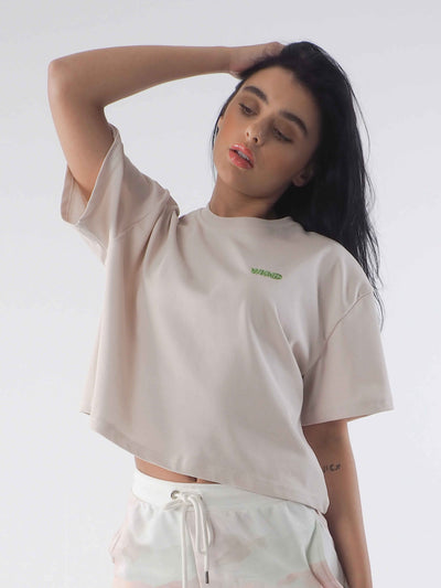 Model has dark hair and is wearing the soft beige cropped tee. The WKND logo is embroidered to the chest.