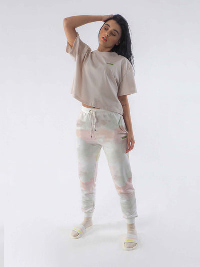 Model wearing joggers in a watercolour tie dye print and oversize cropped tee in soft beige.