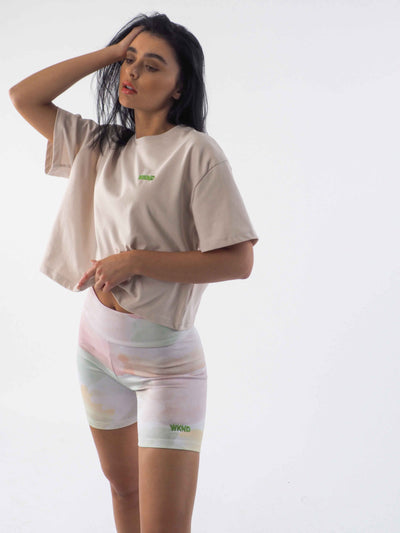 Model is wearing a cropped oversized tee in soft beige and matched it with the watercolour tie dye cycling shorts