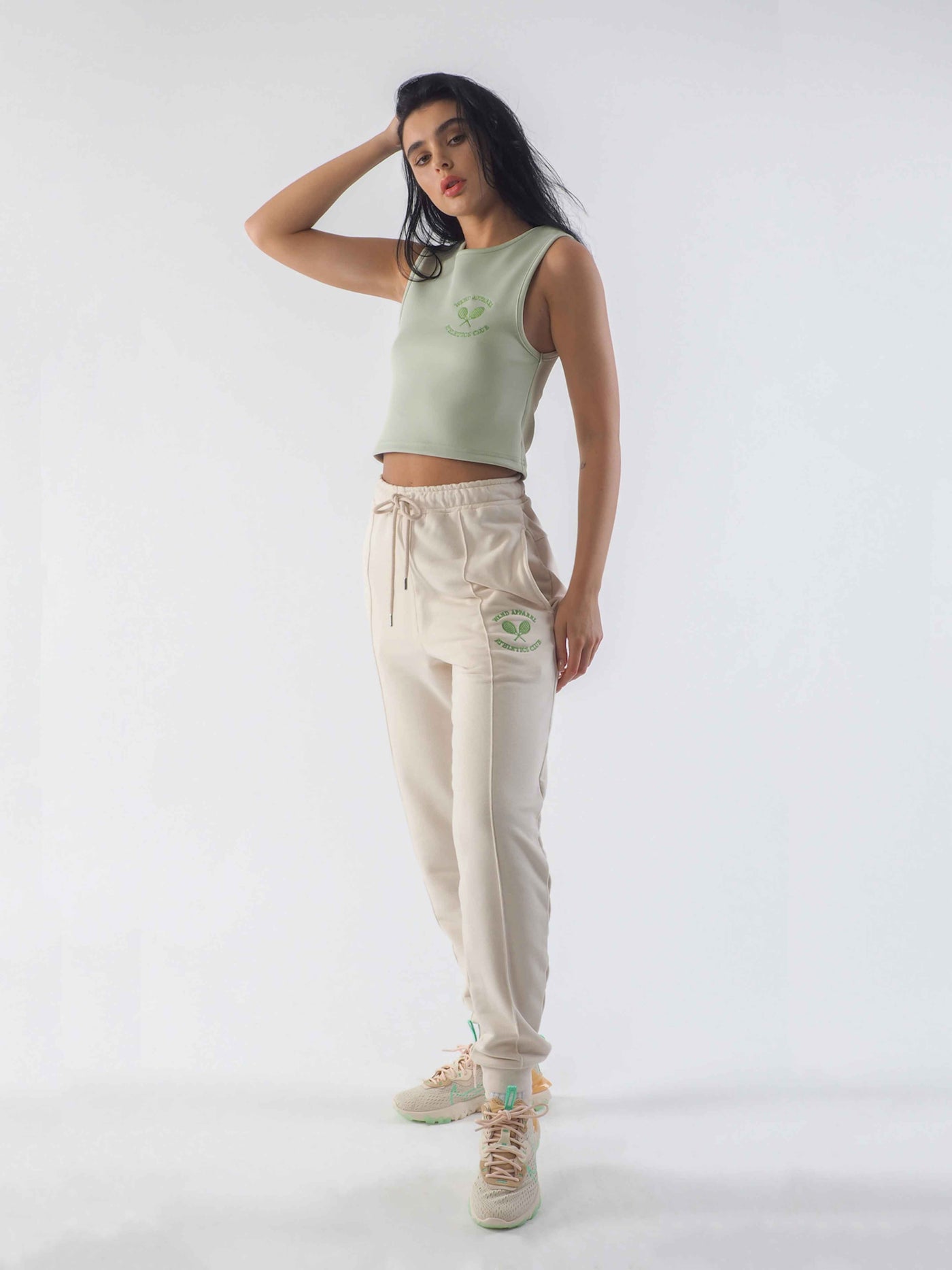 Model is wearing joggers in the colour eggnog with a cropped jade green vest. Both have the WKND Apparel embroidery.