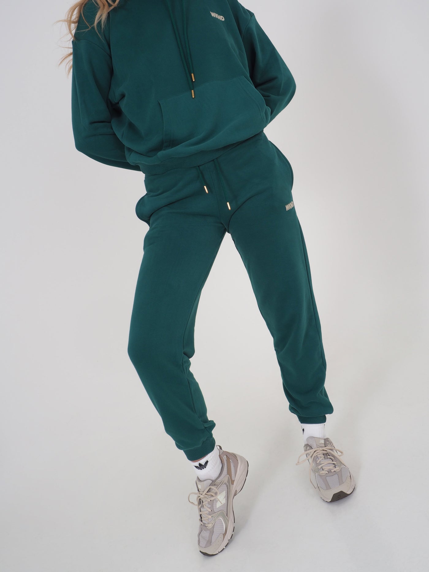 Model is wearing green joggers and matching hoodie.