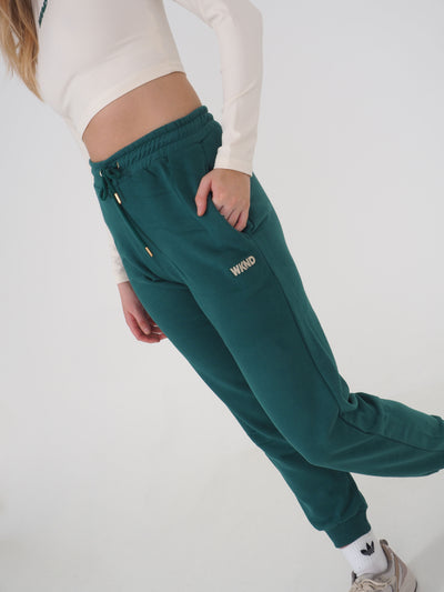 Close up of model wearing green joggers and eggnog crop top with long sleeves. 