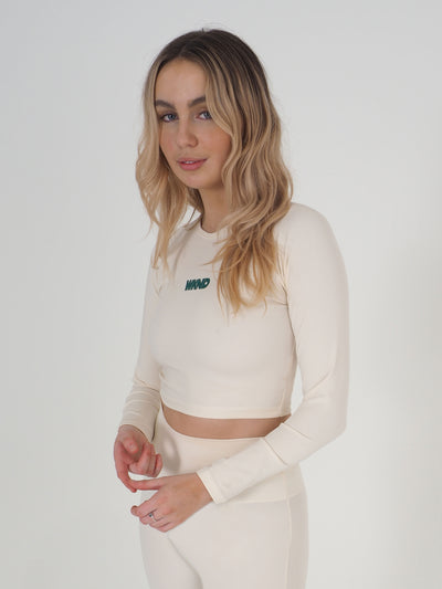 Blonde model is wearing a long sleeve crop top and leggings in eggnog cream.  The WKND logo is green and printed centrally to the chest.