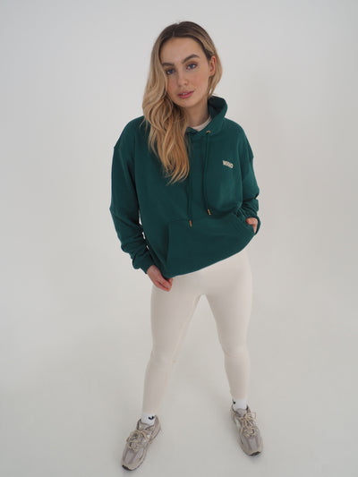 Model is blonde and wearing a green hoodie with eggnog leggings.